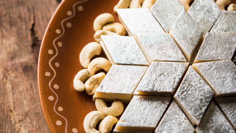 A tray of Kaju Katli arranged in diamond shapes, showcasing the rich golden color and smooth texture of this classic Indian sweet.
