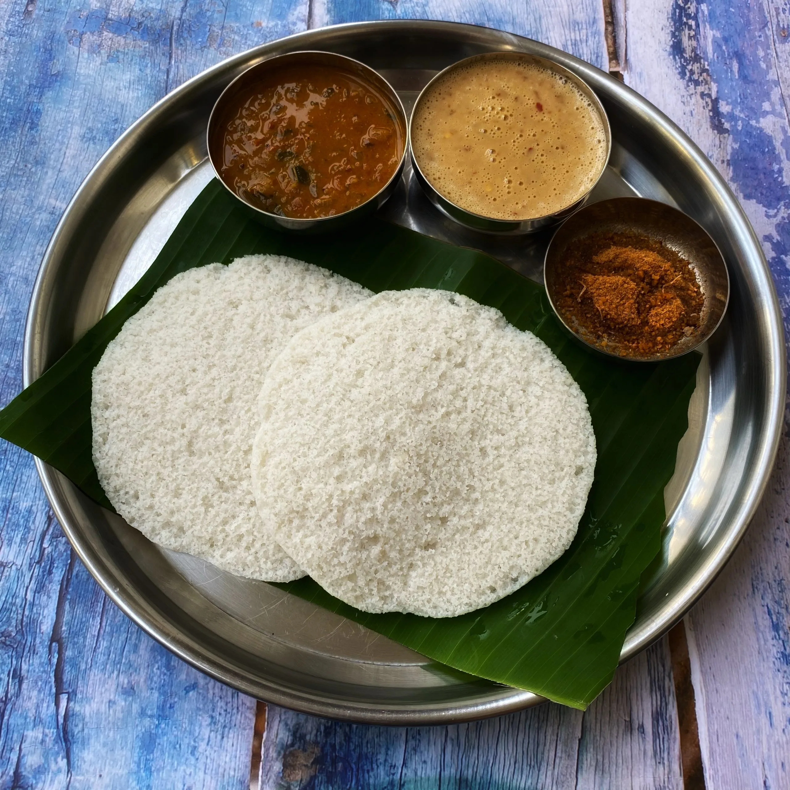 A Plate Of Fluffy Idlis Served With Coconut Chutney And Sambar In A Traditional South Indian Setting.