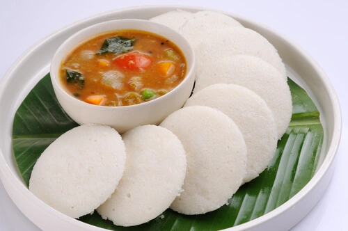 A family enjoying a meal of idlis at home, illustrating the cultural significance and communal enjoyment of the dish.