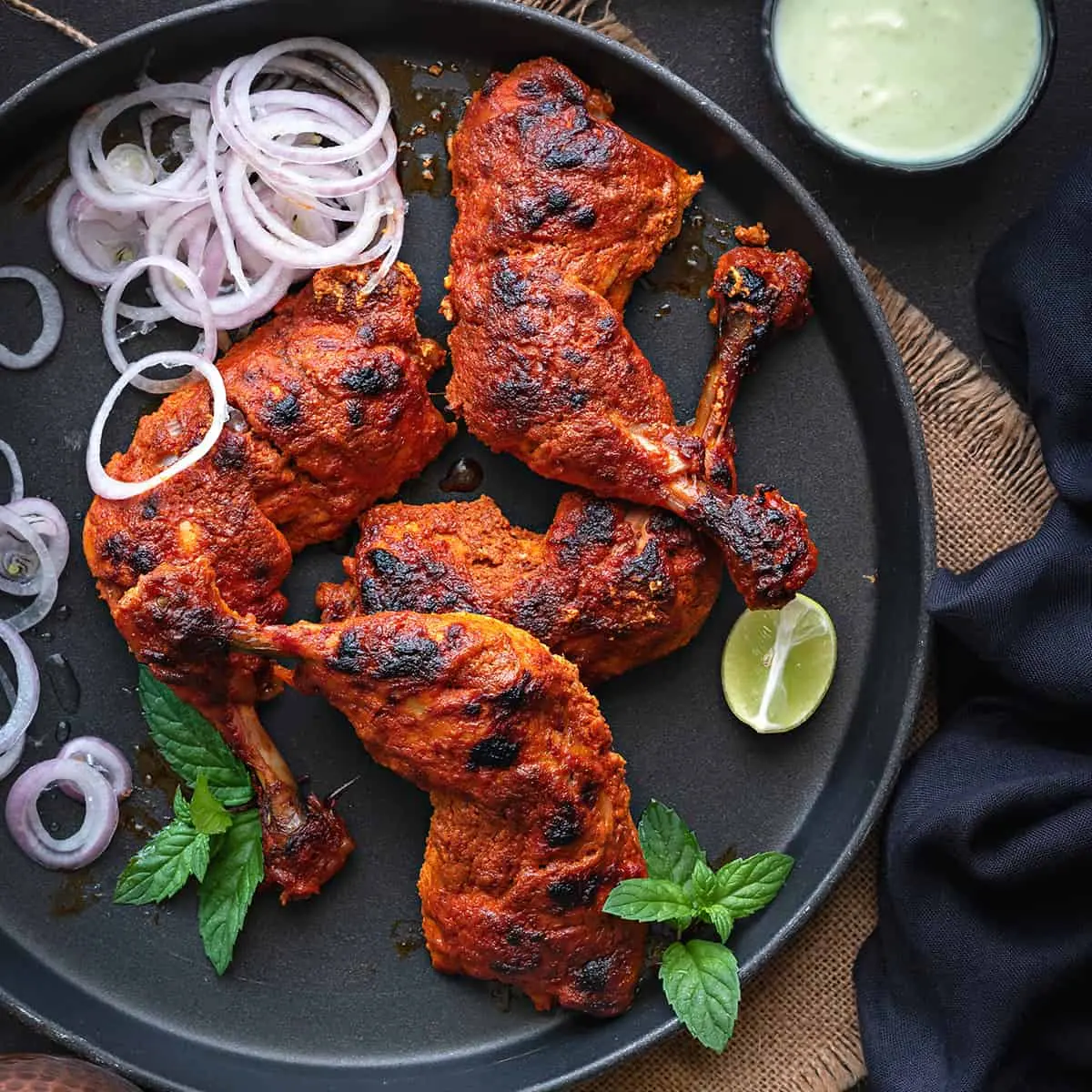 A Vibrant Display Of Tandoori Chicken With Accompaniments Like Biryani Rice, Lemon Wedges, And Fresh Mint Chutney, Celebrating Indian Cuisine.