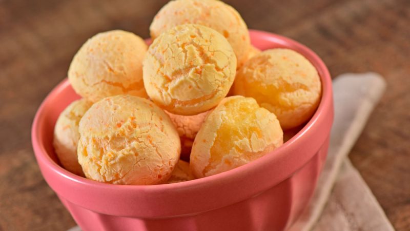 Golden brown Pão de Queijo freshly baked and served in a basket, showcasing their crisp exterior and fluffy interior