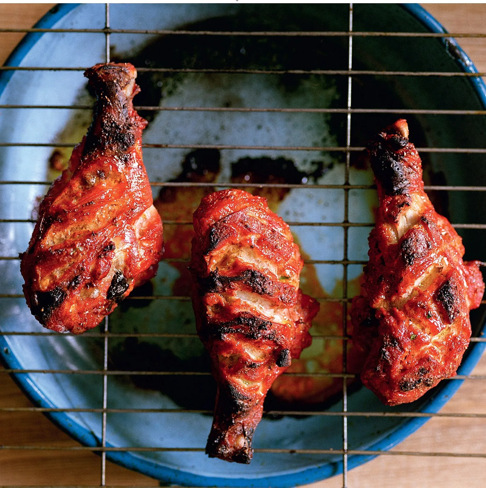 Close-up of marinated tandoori chicken skewers cooking in a traditional tandoor oven, highlighting the charred, smoky exterior.