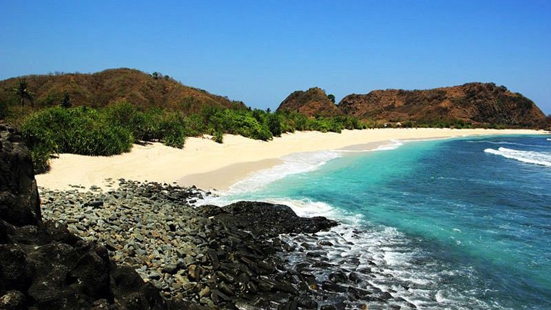 Pemandangan menakjubkan Pantai Semeti dengan formasi batu karang yang unik dan ombak yang tenang, menciptakan latar belakang sempurna untuk berfoto